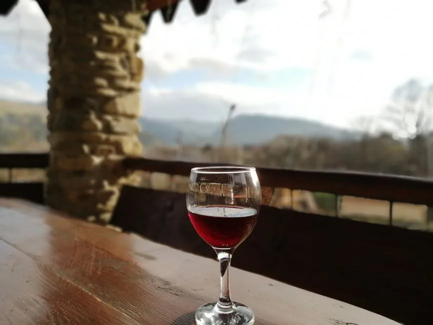Glas Rotwein auf Holztisch mit unscharfer Chianti-Landschaft im Hintergrund