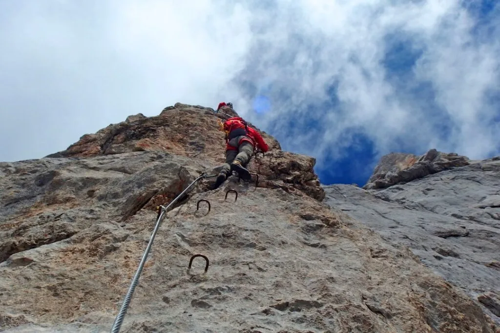 Bergsteiger klettert über eine gesicherte Via-Ferrata mit Stahlbügeln