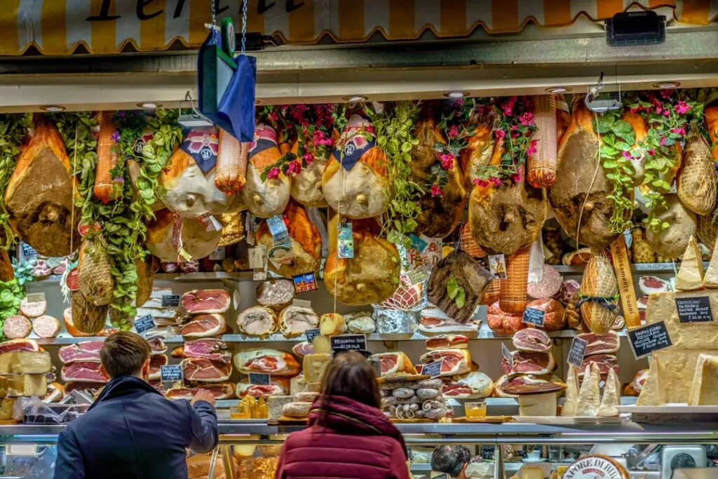 Traditionsreicher Fleisch- und Käseverkauf mit hängenden Schinken an einem Stand in Florenz