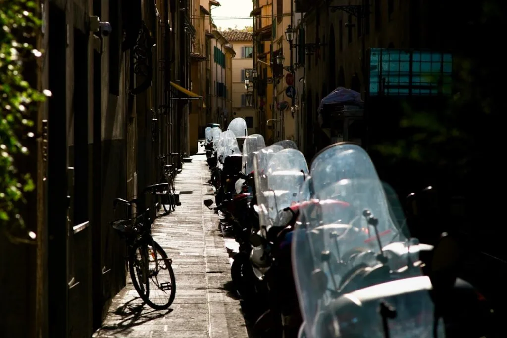 Schmale Florentiner Gasse mit geparkten Rollern und einem Fahrrad