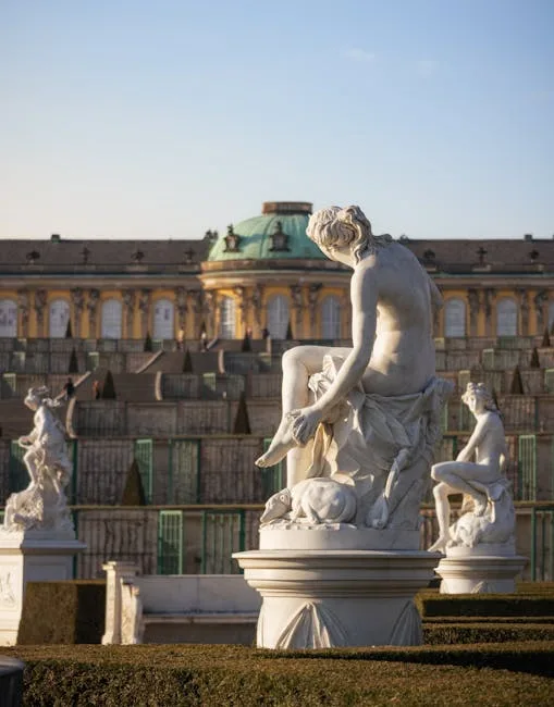 Statues de marbre alignées dans un jardin formel, palais en arrière-plan
