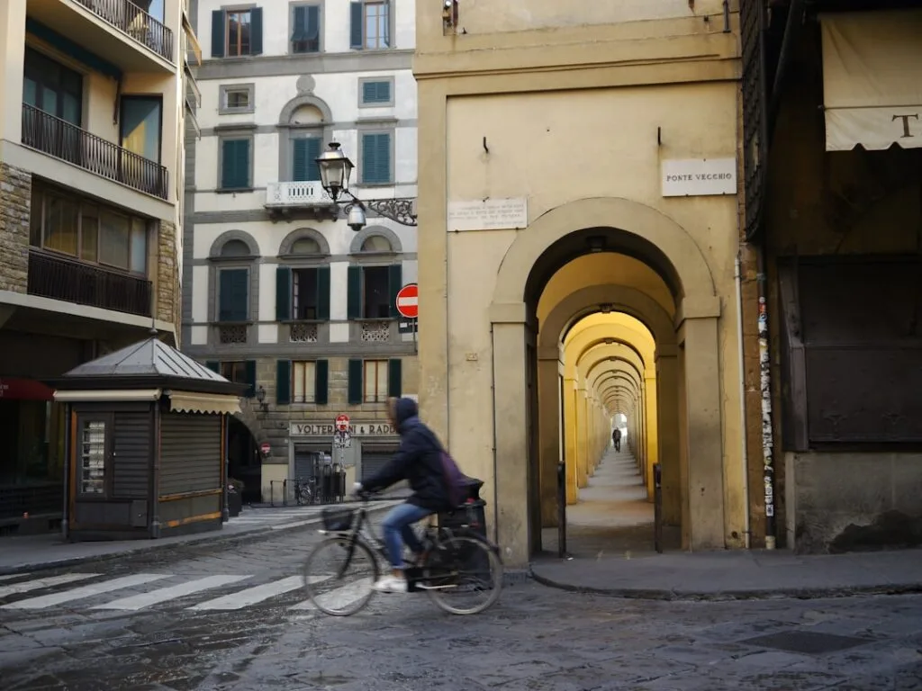 Blick auf Arkadengang am Ponte Vecchio in Florenz mit Radfahrer.
