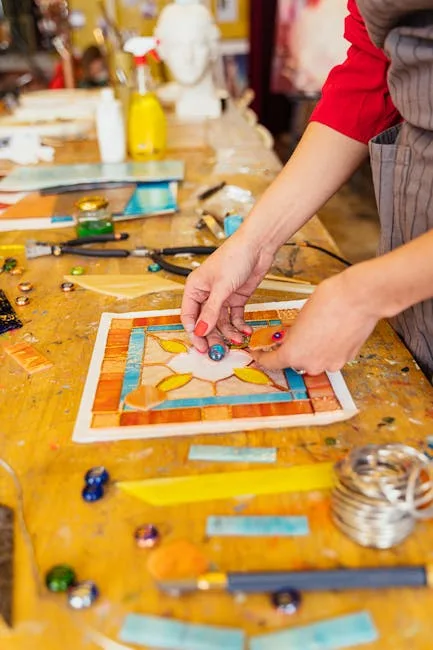 Hände arrangieren bunte Glasmosaiksteine auf Vorlage in Florenz-Workshop
