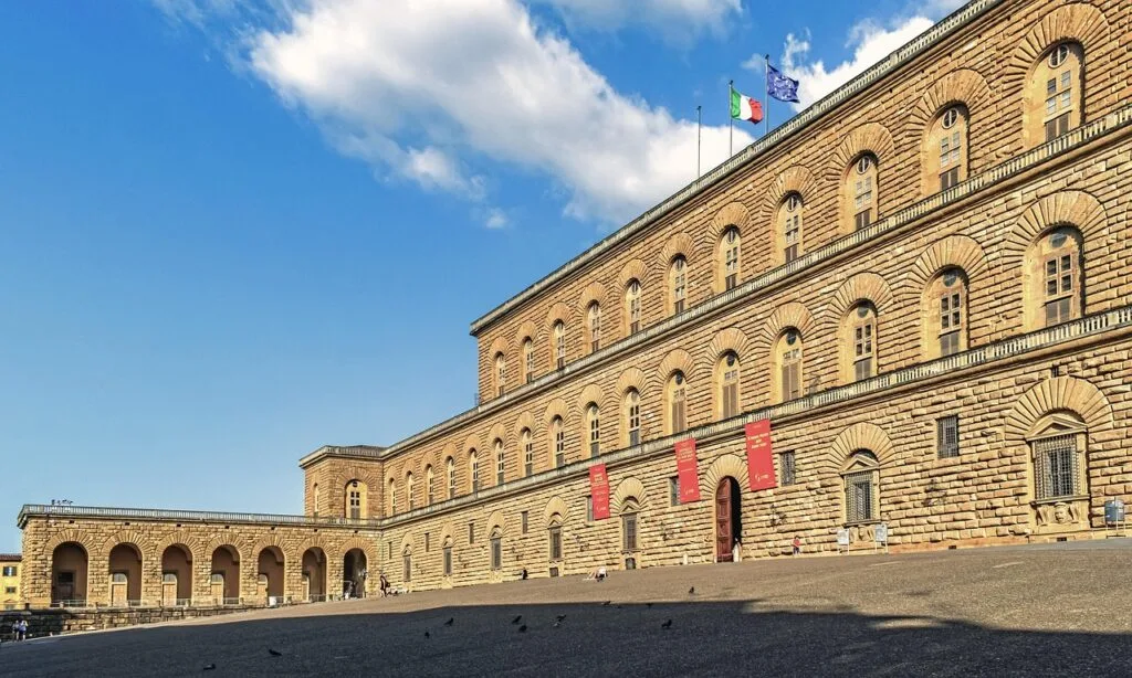 Façade en pierre du Palazzo Pitti avec drapeaux, place calme, Florence