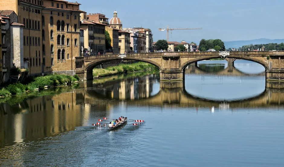 Équipage d'aviron glissant sur l'Arno devant un pont florentin.