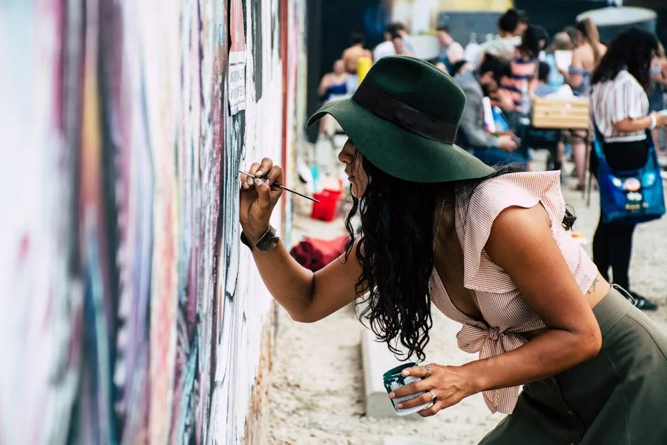 Künstlerin mit grünem Hut bemalt eine Wand bei Street‑Art‑Event in Florenz