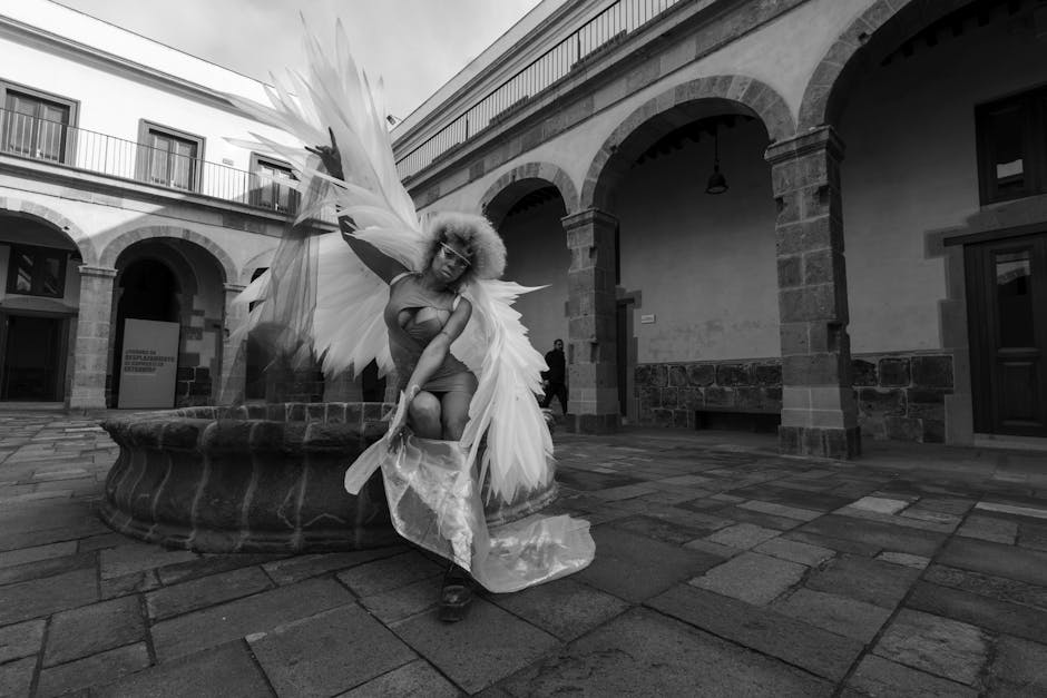 Dancer wearing large feathered wings striking a pose in stone courtyard