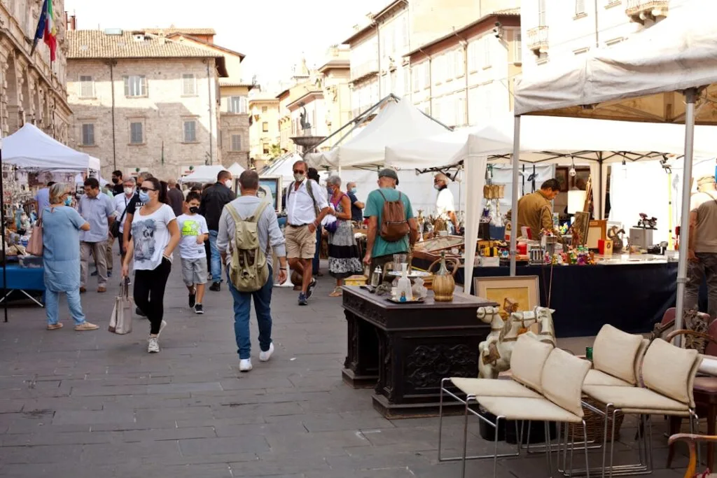 Straßenmarkt mit Vintage‑Möbeln und Besuchern auf einem Platz in Florenz