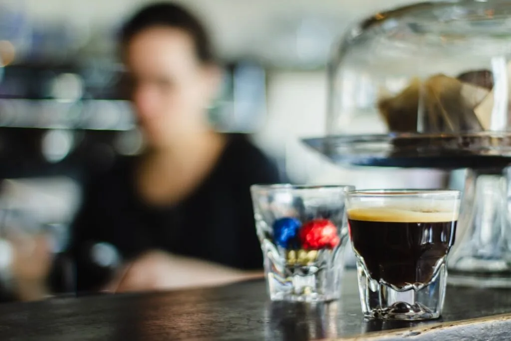 Petit espresso sur le comptoir d'un café florentin, serveur en arrière-plan flou