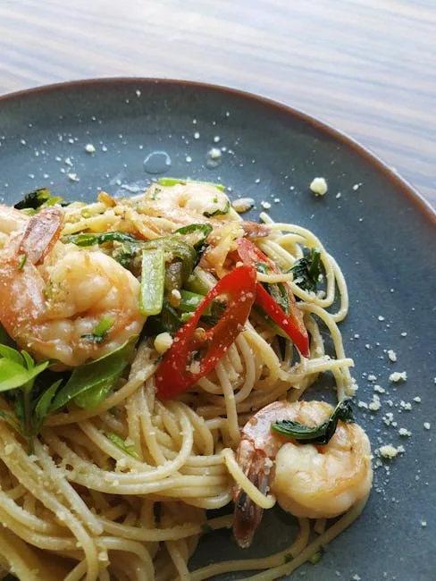 assiette de spaghetti aux crevettes, piments et herbes sur plat