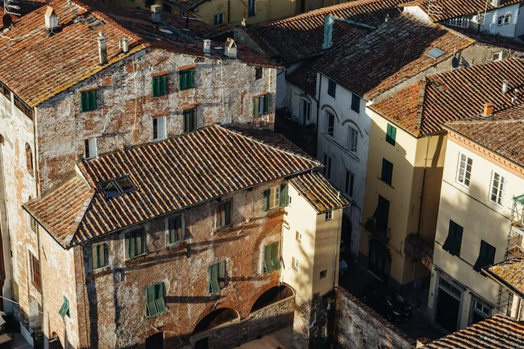 toits en tuiles et façades usées avec volets verts à Lucca