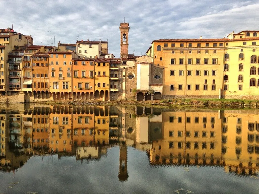 Historische Häuser am Arno spiegeln sich ruhig im Wasser von Florenz
