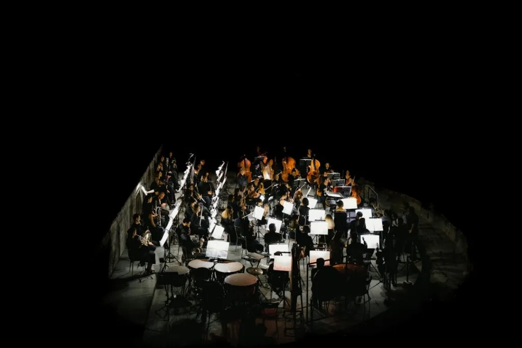 Orchester von oben beleuchtet, Reihen mit Notenständern in dunklem Saal