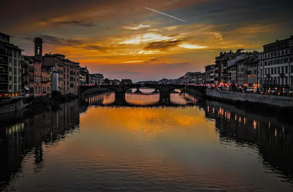 Coucher de soleil orangé sur l'Arno à Florence, reflets dorés