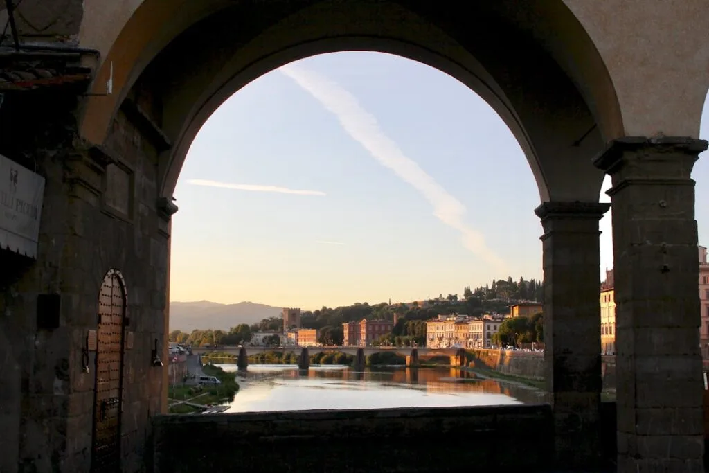 Vue encadrée par une arche sur l'Arno et Florence distante.