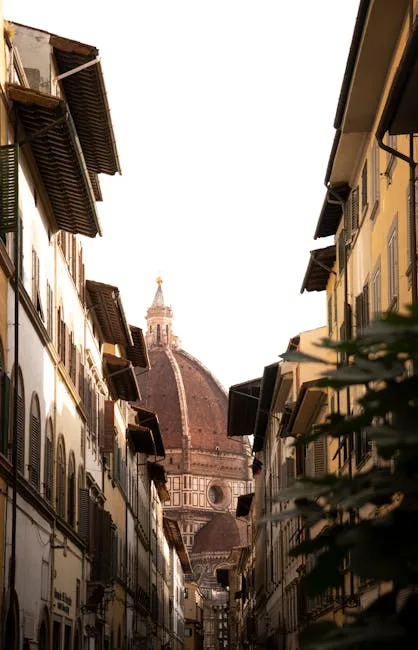 Ruelle étroite bordée de façades, perspective sur la coupole du Duomo de Florence.