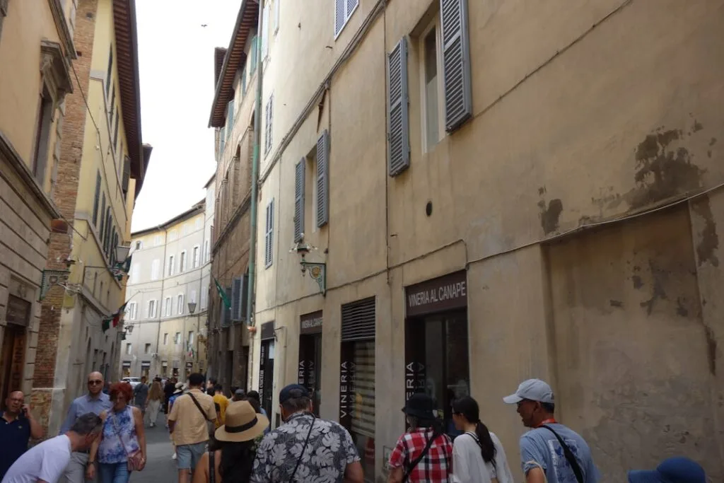 Enge Gasse in Siena mit Touristen und historischen Fassaden