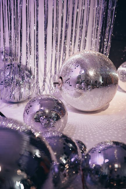 Shiny disco balls and silver tinsel under purple ambient lighting