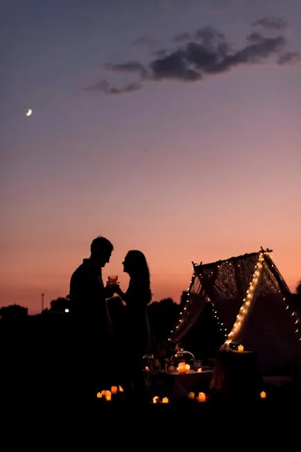 Paar in Silhouette bei romantischem Abendpicknick unter Lichterketten