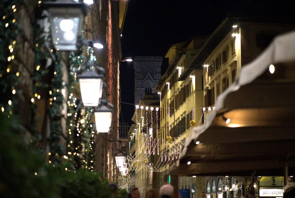 Rue piétonne illuminée à Florence, guirlandes de Noël et clocher visible