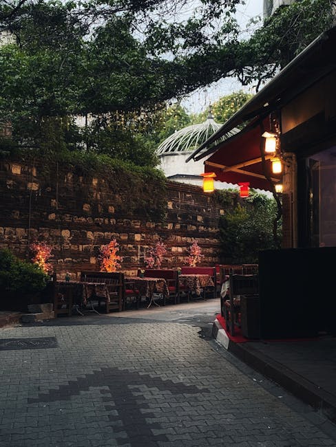 ruelle pavée avec terrasses éclairées et mur en briques ombragé