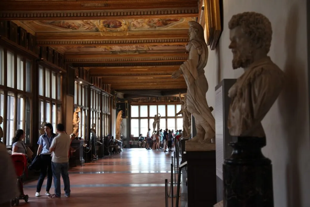Galerie des Offices à Florence, statues alignées et visiteurs marchant