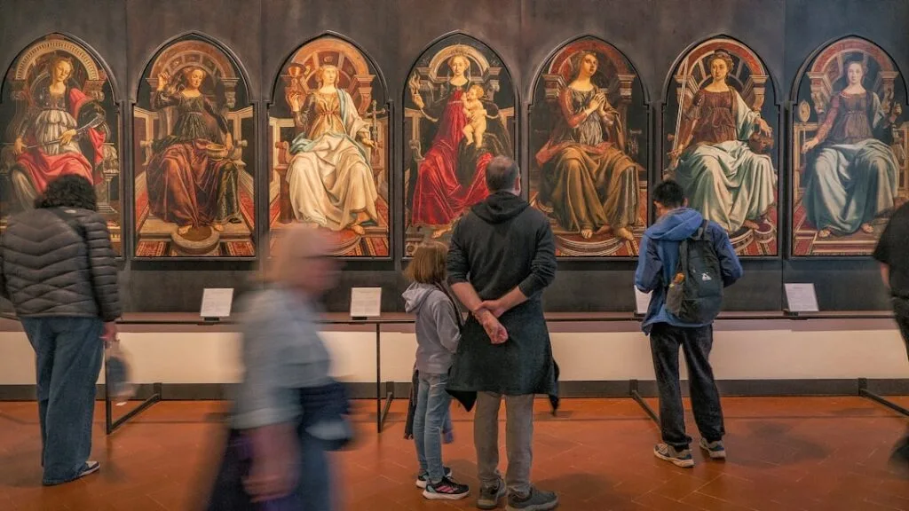 Visiteurs regardant une série de panneaux religieux exposés aux Uffizi, Florence