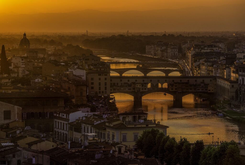 Golden sunset over Florence showing Ponte Vecchio and arched bridges.