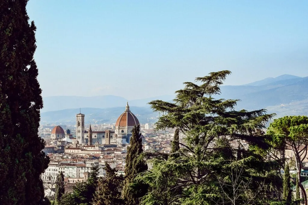 Vue du Duomo de Florence encadrée par des cyprès et collines