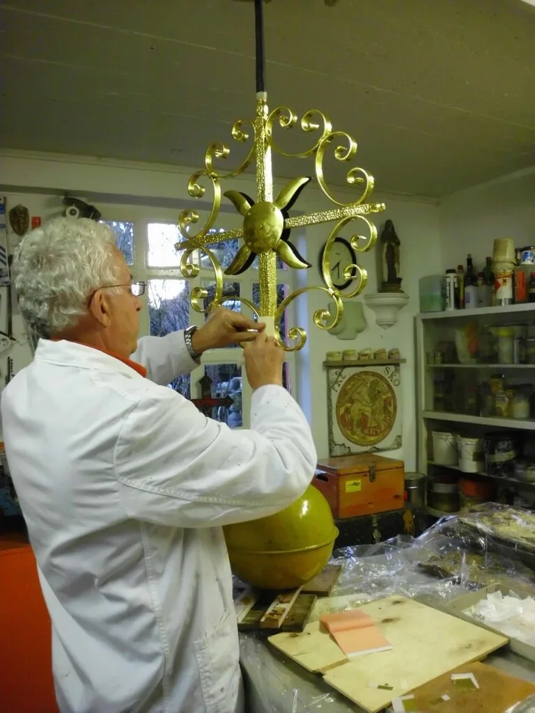 Artisan appliquant dorure sur ornement métallique dans un atelier florentin